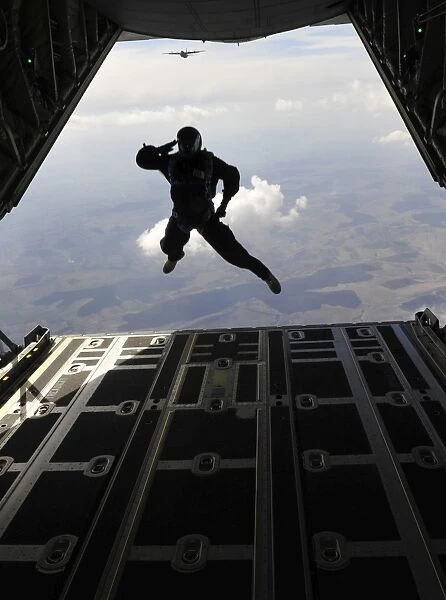 A paratrooper salutes as he jumps out of a C-130J Super Hercules