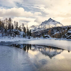 Snowy peak of Sasso Moro reflected in the frozen lake MufulA¨, Malenco Valley