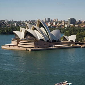 Sydney Opera House built in 1973, designed by Jorn Utzon, probably the most iconic symbol of the city, with a tourist ferry crossing the harbour towards nearby Circular Quay, Sydney, New South Wales