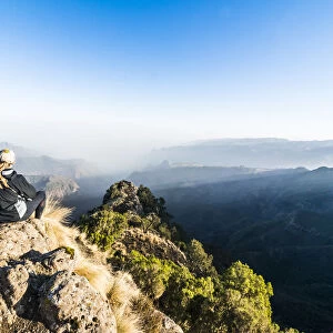 Woman enjoying the early morning sun on the cliffs, Simien Mountains National Park