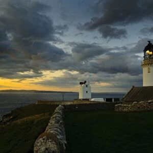 View of clifftop lighthouse at sunset, most northerly point on mainland, with island of Hoy in background